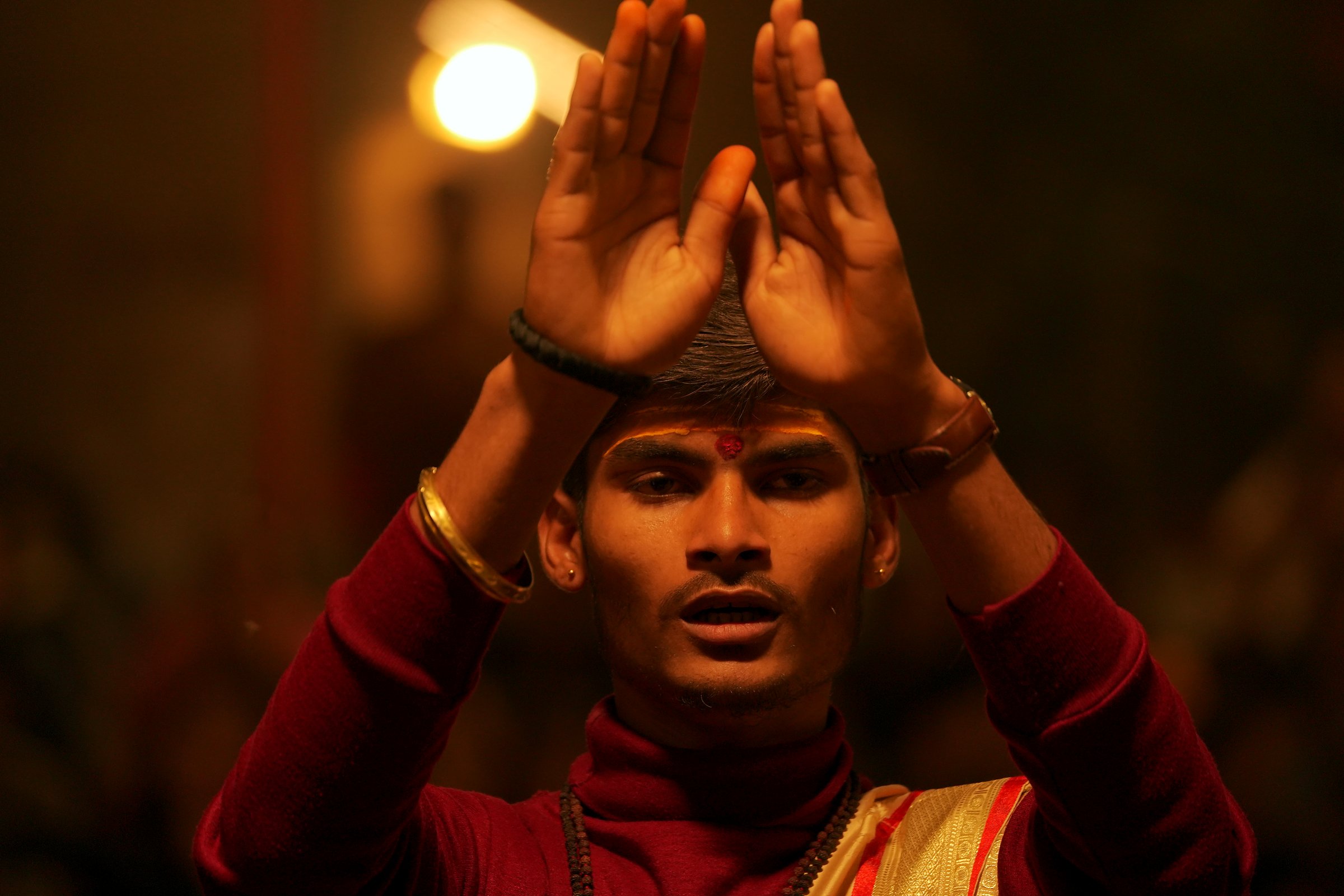 Young priest raising his hands during the Ganga Aarti