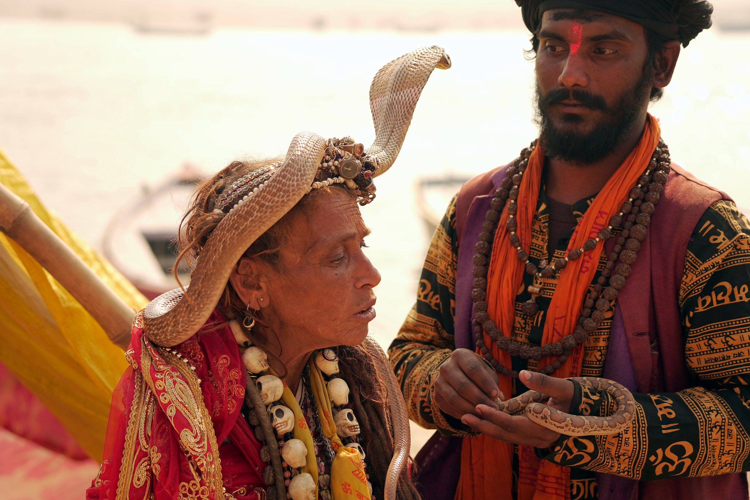 A holy woman with bangles and a snake, talking with a sadhu on the ghats
